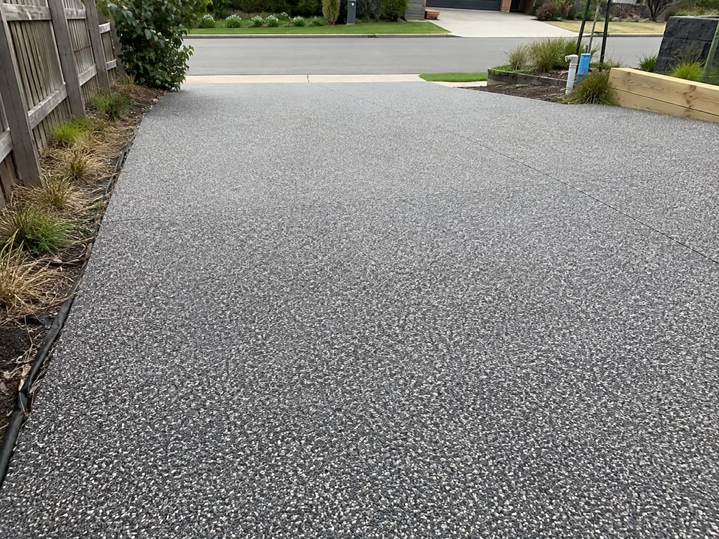 Freshly sealed exposed aggregate driveway at a landscaped Melbourne home