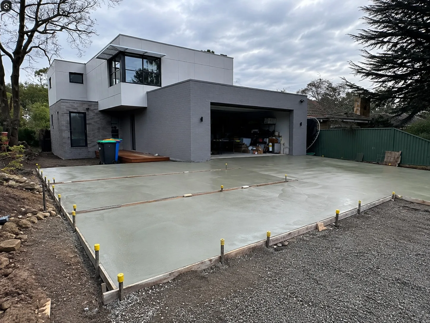 Freshly poured plain concrete driveway set out with pegs at a modern Melbourne home
